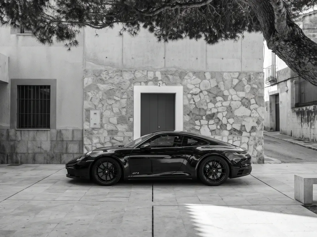 Black Porsche 911 GT3 parked outside a stone house
